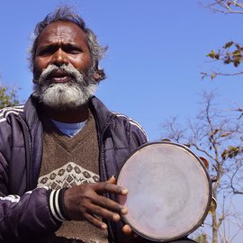 Rajkishor Sunani sings a song while people gather around him to listen