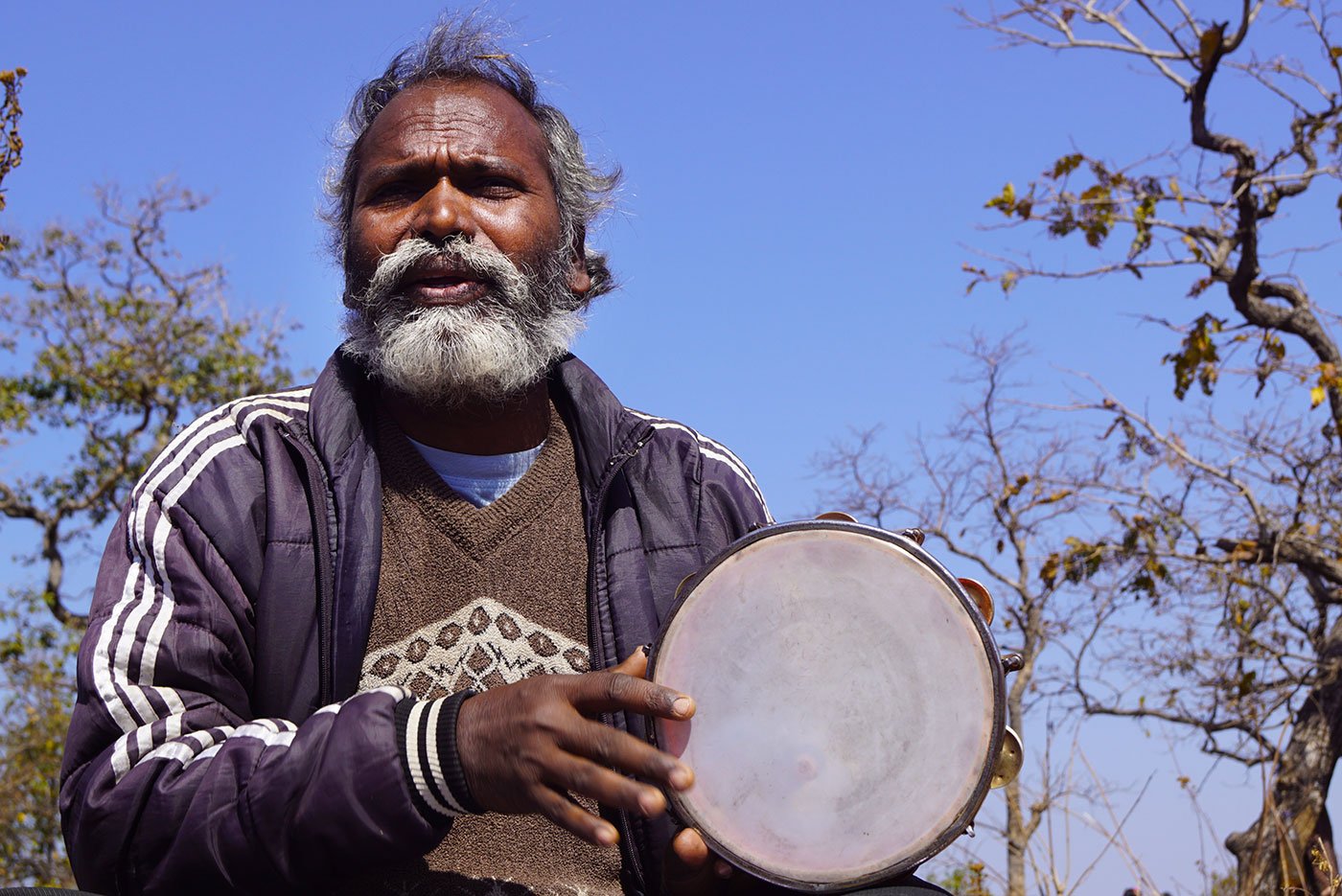 Rajkishor Sunani sings a song while people gather around him to listen