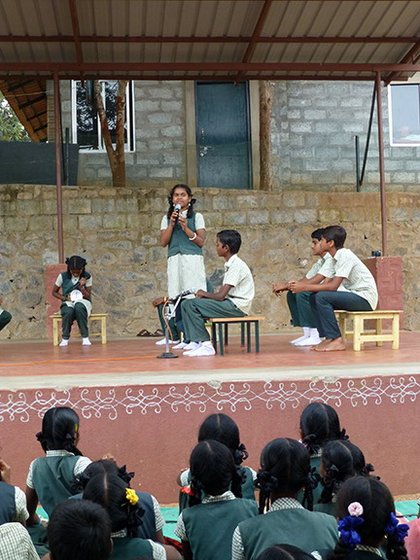 Left: Vidya Vanam students, most of them from Adivasi and Dalit communities, begin their spirited and informed debate on genetically modified crops. Right: The moderator looks at the clock she is using as a stopwatch, while a debater makes her point