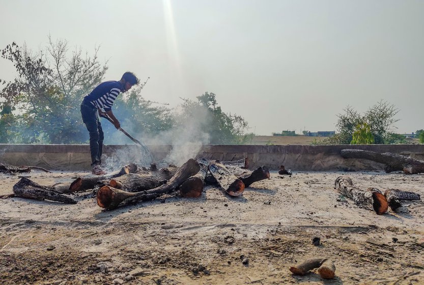 Ganesh (in blue and white t-shirt) gathers the ashes after cremation of bodies. He helps Rama Gandewad, his father-in-law, in the cremation work