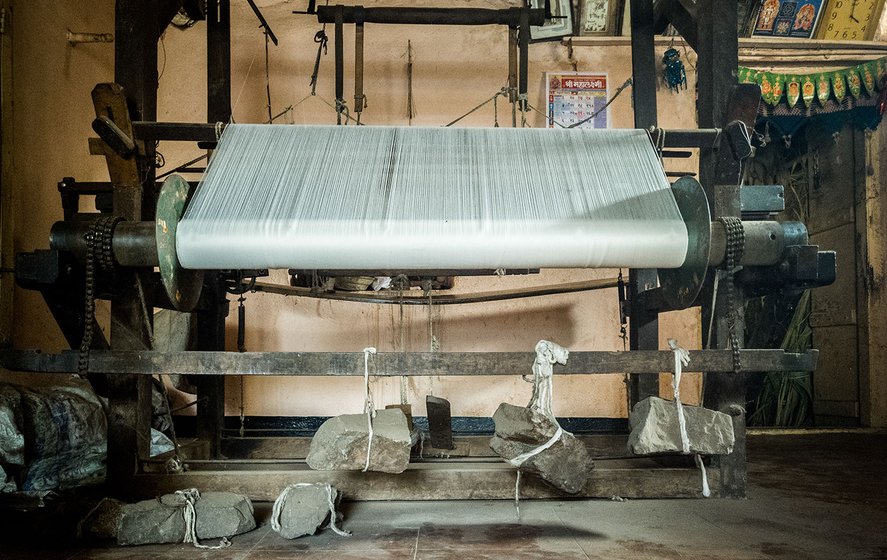 Stones are attached to the handloom to help control the flow of thread towards the heddle from the mounted beam