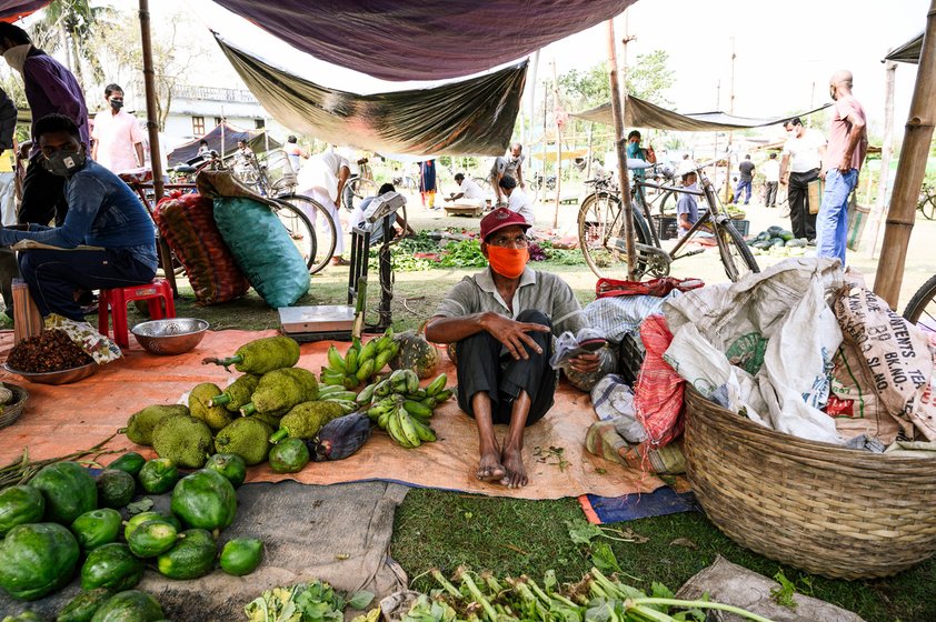 Left: For 23 years, 47-year-old Prafulla Debnath has been doing odd jobs at the regular Samabay Krishi Unnayan Samity Market (now closed for the lockdown). He carries sacks to be delivered to the houses of customers, and carries goods from vehicles to shops. And he sweeps the whole market – picking up Rs. 2 per day from each vegetable vendor and Re. 1 per day from the other shopkeepers. But now, with the market shifted to the field in Dutta Para, even his bare earnings have halved, though some of the vegetable vendors arrange for breakfast and lunch for Debnath. “If I do not clean, the market will be dirty,” he says. “If I clean the market then everyone will know my name. Nobody will work like me!” Right: Since the market is open for only a few hours, many buy at the last minute, hoping for low prices. Khoka Roy, 50, was a carpenter, then he ran a small grocery shop from home, and is now out selling in the market due to the lockdown. From Rs. 400-500 per day, his income has dropped to Rs. 200-250. “With the police patrolling, people are not leaving their houses,” he says. “You tell me, how we can sell vegetables?"

