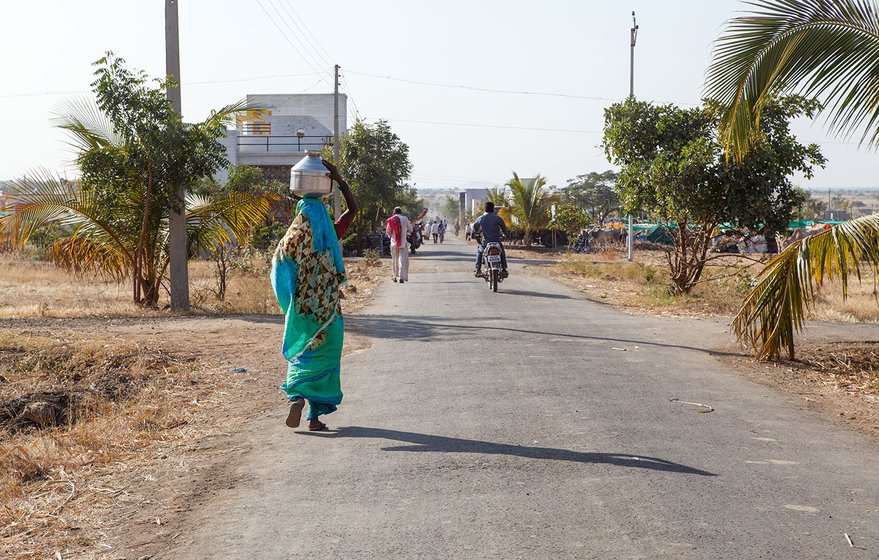 Lakshmi walking back at a brisk pace to her tent after filling water for her own use