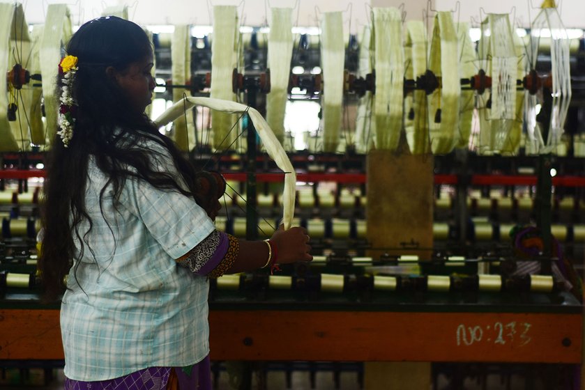 Another worker in the yarn factory changes the spinning wheel