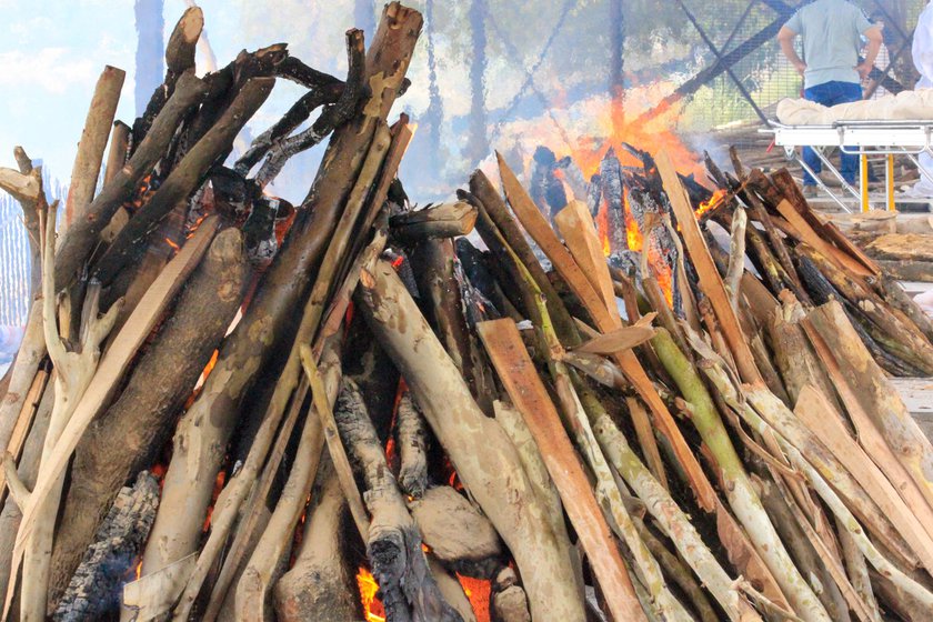 Left: The dead body of a Covid-positive patient resting on a stretcher in the crematorium premises. Right: A body burning on an open pyre at Nigam Bodh Ghat