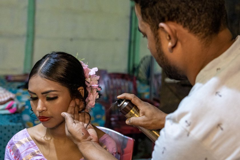 Mukta delicately twists Rumi's hair into a bun, adds a few curls and flowers, and secures it all with hairspray.