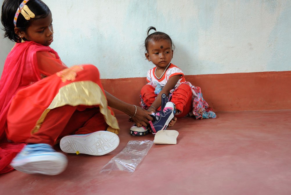 A little girl who has not yet been named gets her first pair of shoes from a non-governmental organisation 