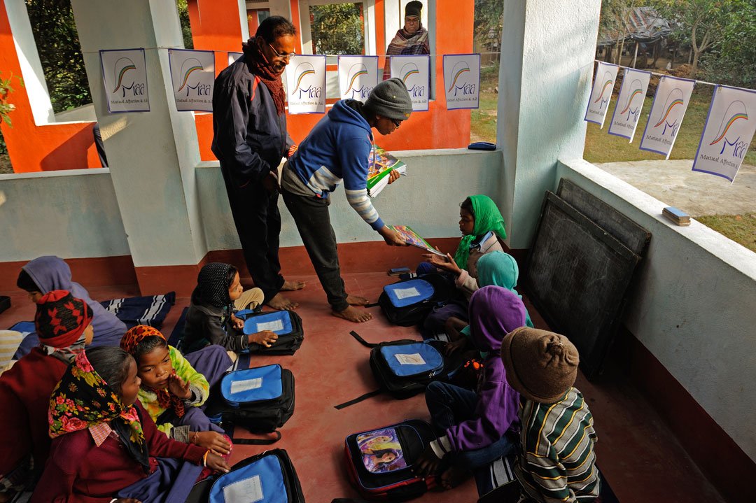 Reba Murmu distributing exercise books to students. This is one reason parents too support this school – everything here is given for free