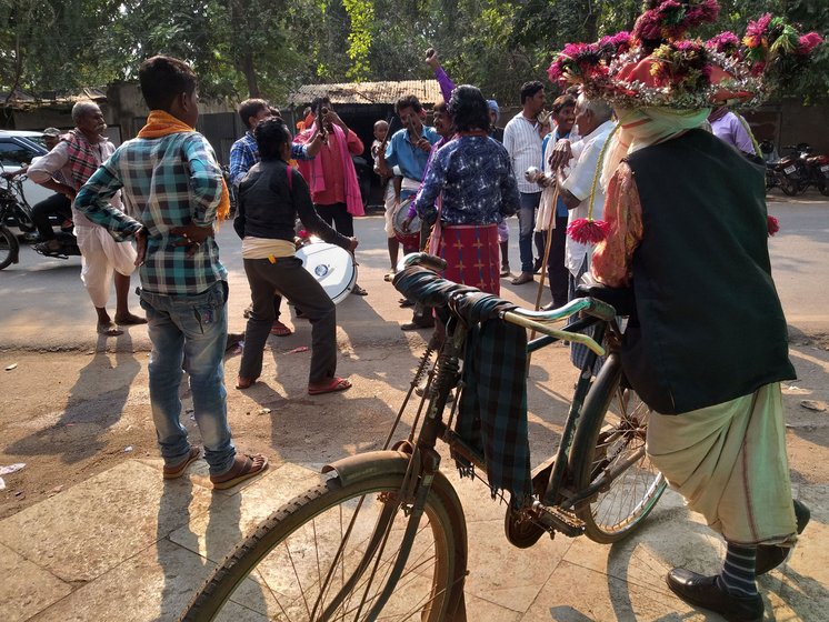 A member of the Raut community (with the cycle) watches and evaluates a Gana-baja performance