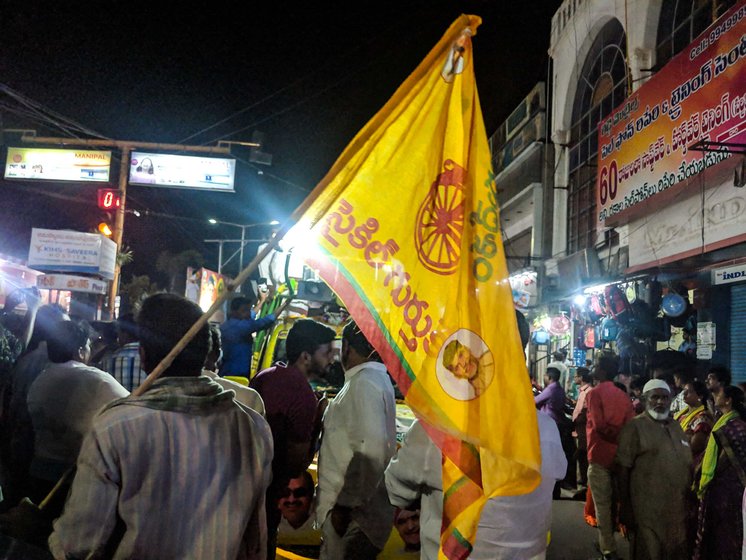 A farmer, who supports Naidu's TDP, watches as a TDP leader campaigns in Anantapur city