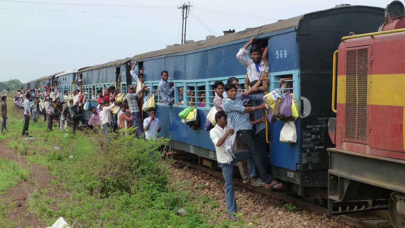 An overcrowded train with people hanging out the doors