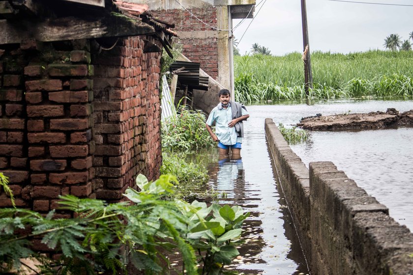 Farmer wades through flooded lane