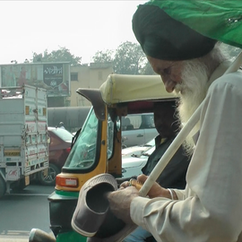 Old Sikh farmer walking on the street. Holding shows and biscuit packet