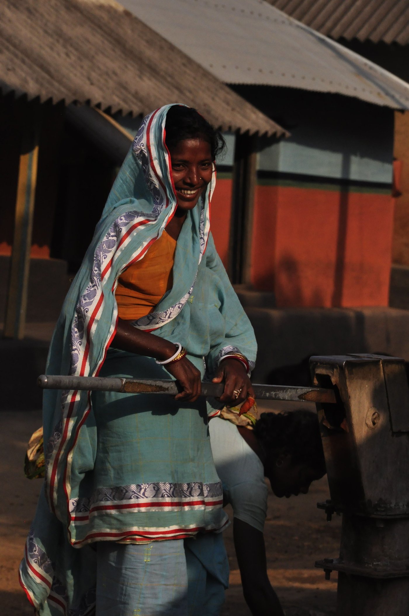 Santhal woman pumping a tubewell to collect water