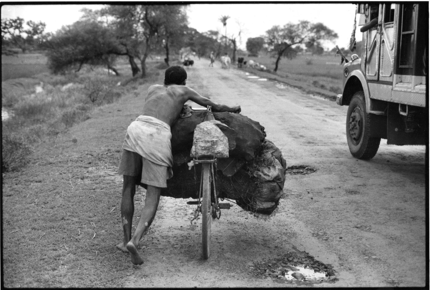 Man pushing heavy load of coal on bicycle